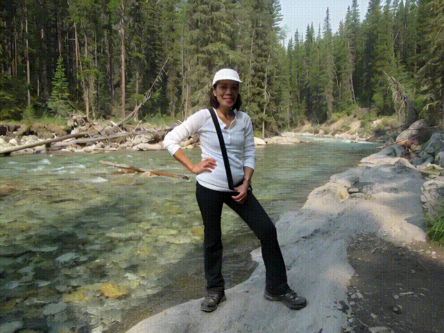 A video of a woman standing beside Cascade River in Banff National Park.