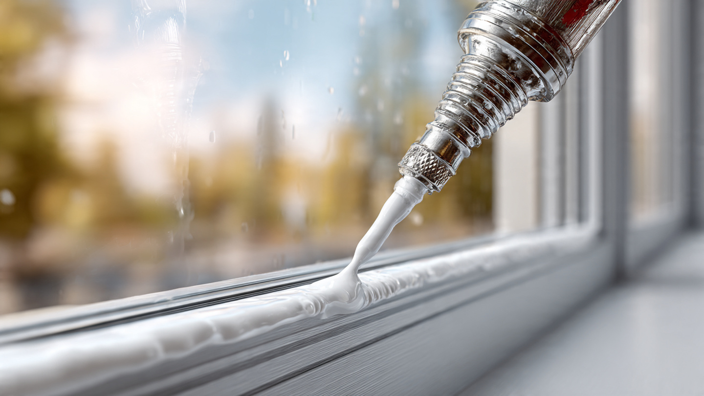 Hand applying high-end silicone sealant to a structural joint frame showing precise bead extrusion