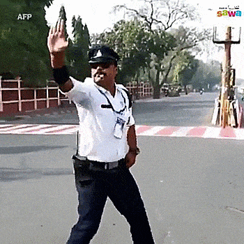 Traffic police officer performs dancing hand signals to direct vehicles at a busy intersection.
