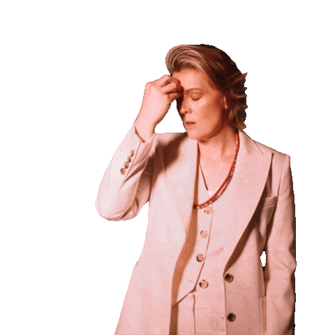 A person in a white suit massages their forehead, expressing stress or a headache against a black background.