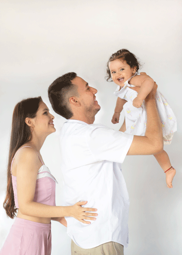 adres sonrientes, con su hija en brazos del padre, simulando un vuelo, mostrando alegría y conexión familiar.