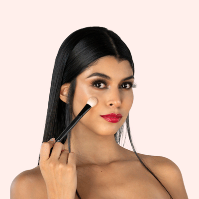 Mujer aplicando maquillaje con brocha, enfoque en detalle de maquillaje.