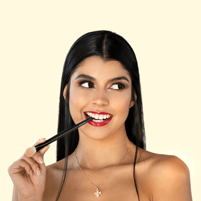 Mujer mordiendo delicadamente brocha de maquillaje, captura de detalle en su rostro.