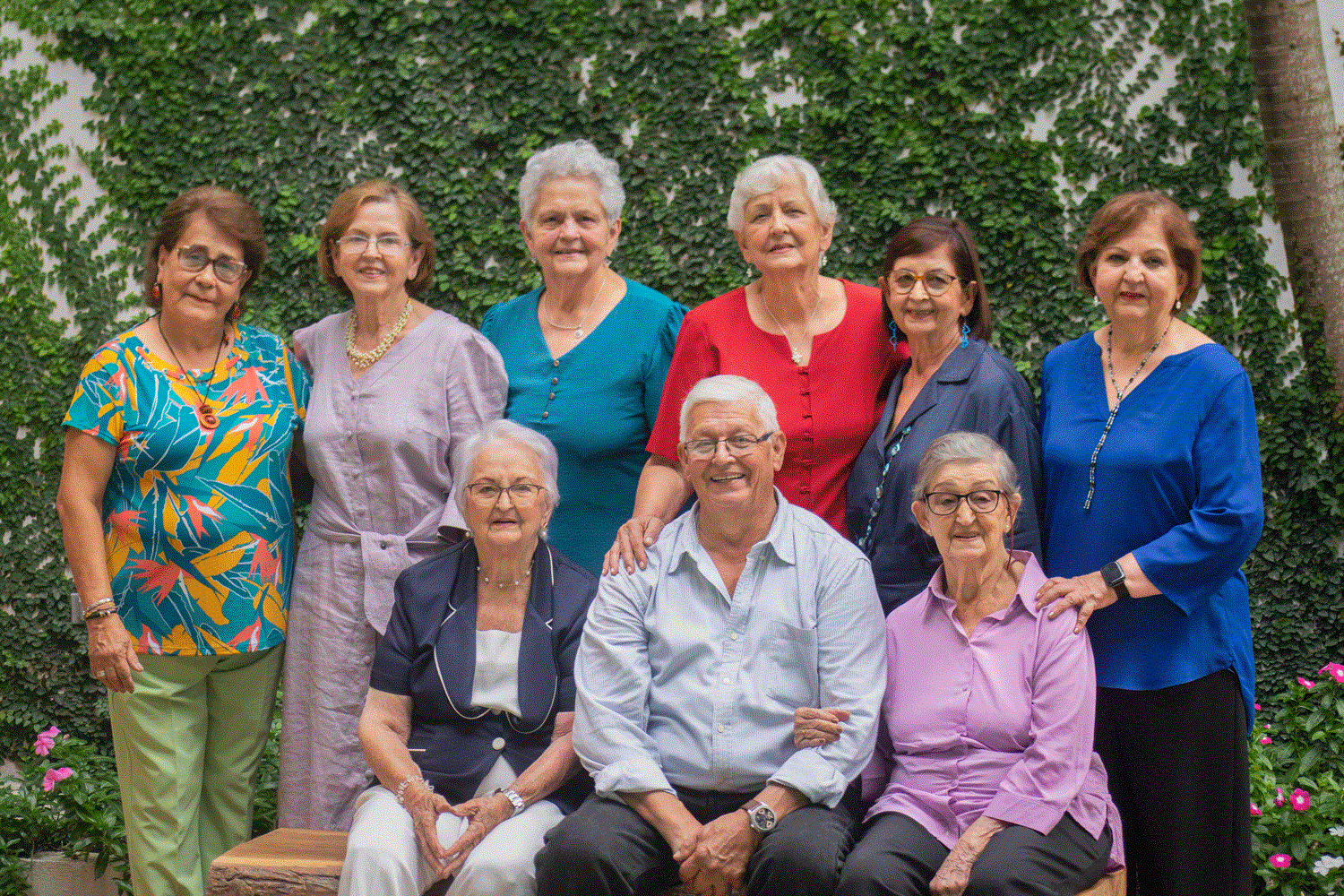 Nueve ancianos reunidos en un emotivo reencuentro familiar, sonrientes y mirando a la cámara con expresión de felicidad.