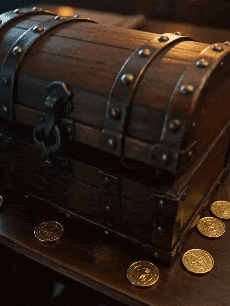 Rustic wooden treasure chest with iron hardware and scattered gold coins on a table.