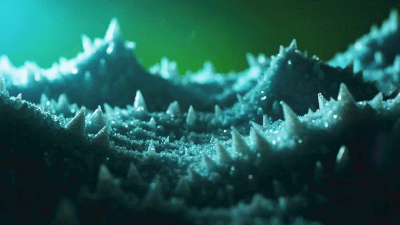 Macro view of glowing blue crystalline formations with sharp peaks in a mystical green landscape.