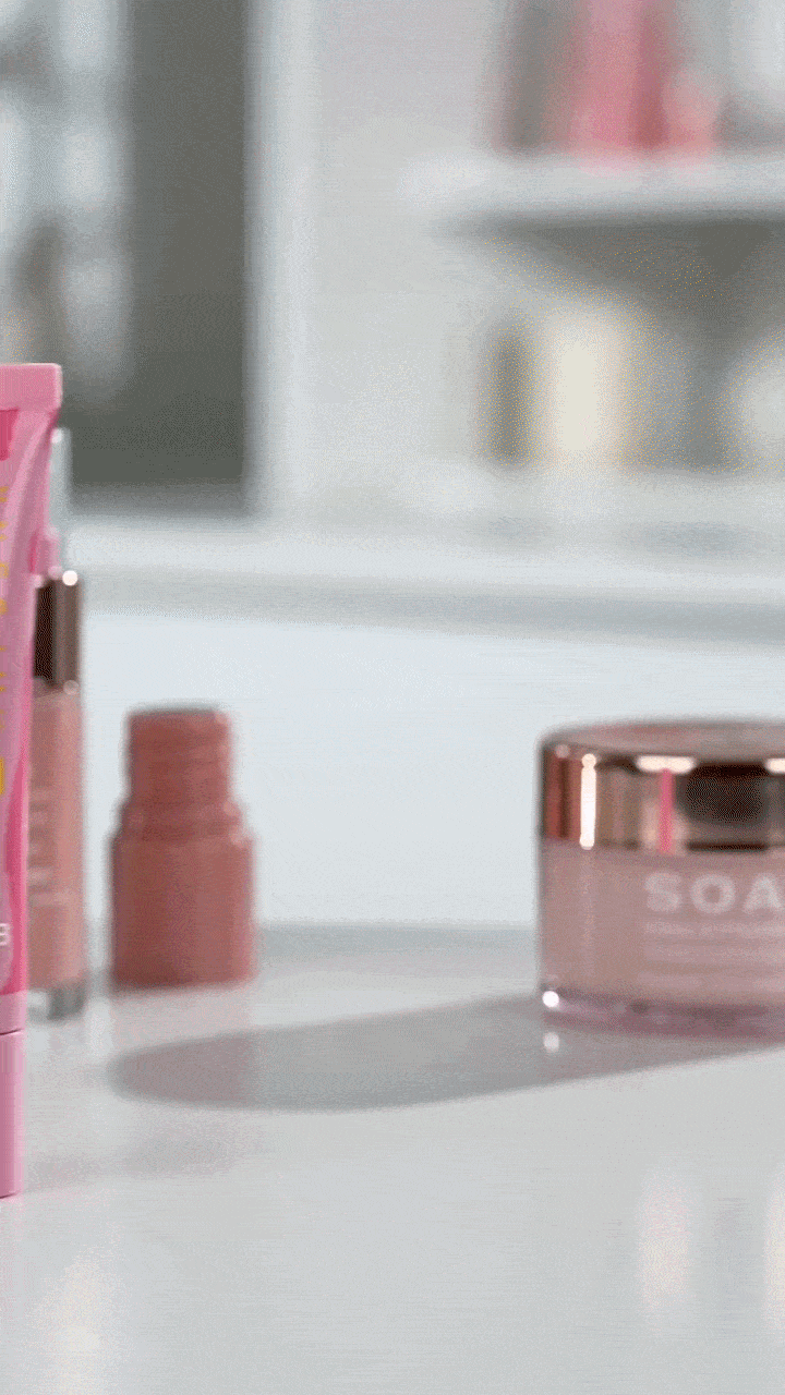 Soap and Glory skincare products including pink lotion tube and face cream on a white counter.