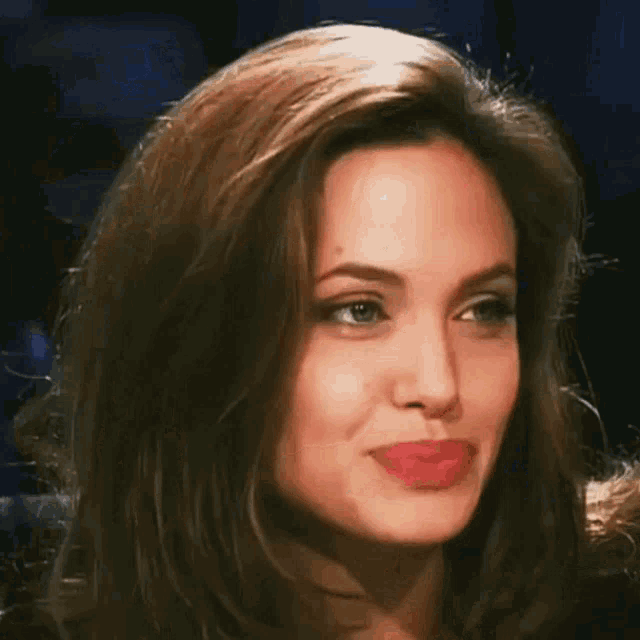 Close-up portrait of actress Angelina Jolie smiling during an interview with her signature red lipstick.