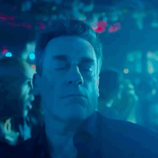 Jon Hamm as Don Draper dancing at a club with blue neon lighting in Mad Men.
