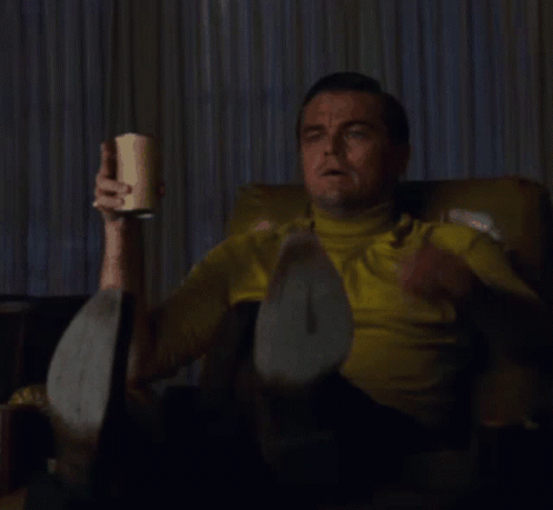 Leonardo DiCaprio pointing at a TV screen while holding a drink in the Once Upon a Time in Hollywood meme.