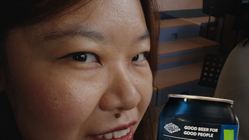 A smiling woman holding a can of craft beer can with the slogan Good Beer for Good People.