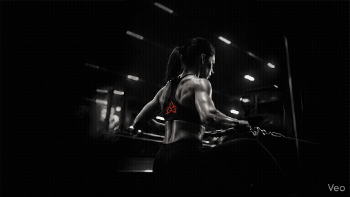 Muscular woman performing a seated cable row exercise in a dark gym for back strength training.