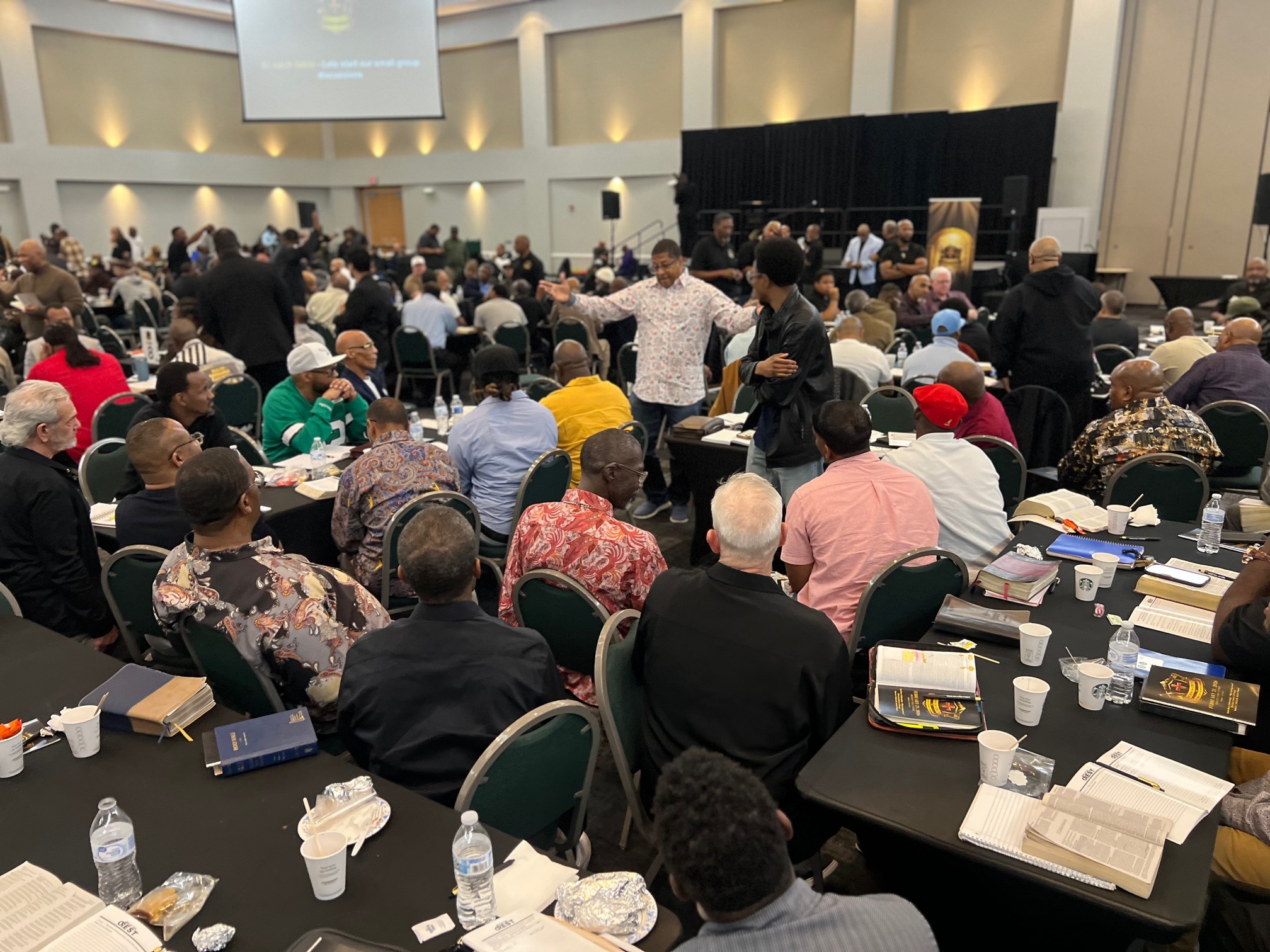 Man in light shirt speaking with raised hand