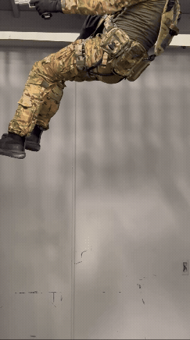 a special forces operator descending on a technora cord with rapid rappel system with a hand gun