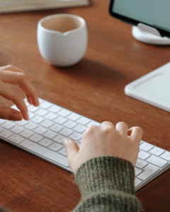 a person typing on a keyboard with a cup of coffee