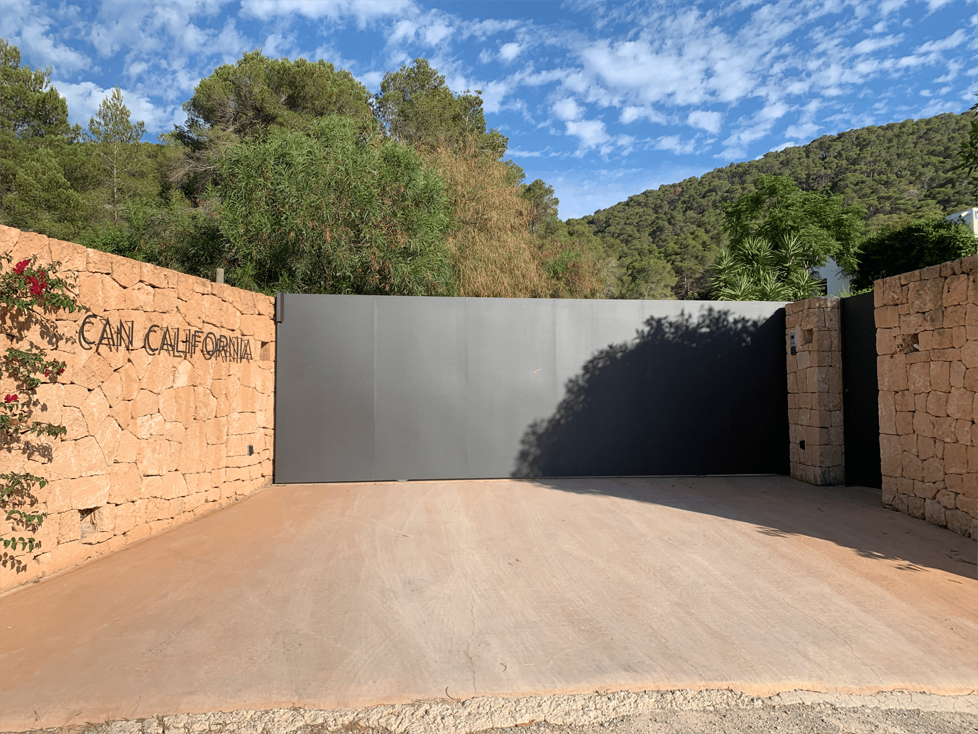 Minimal sliding gate integrated in stone wall, Ibiza