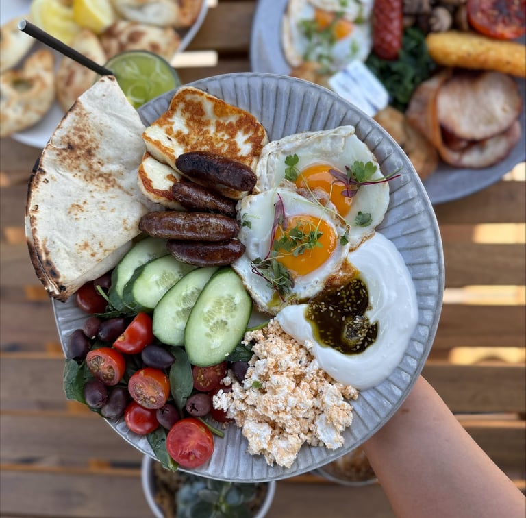 Breakfast plate with eggs, haloumi, olives, cucumber and flatbread