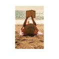 A woman on the beach lies on her back and reads a book