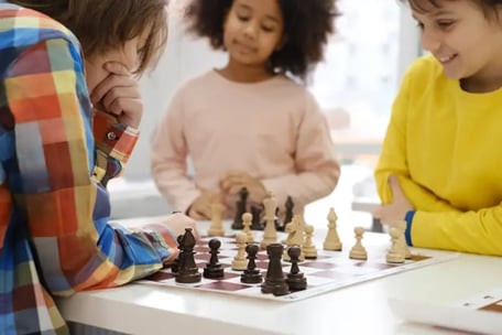 a group of children playing chess in a room