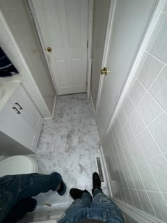 Small bathroom renovation featuring gray marbled floor tiles, white wall tiles, and a compact vanity.