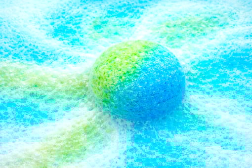Extra large blue and green bath bomb fizzing with rich, colorful foam.