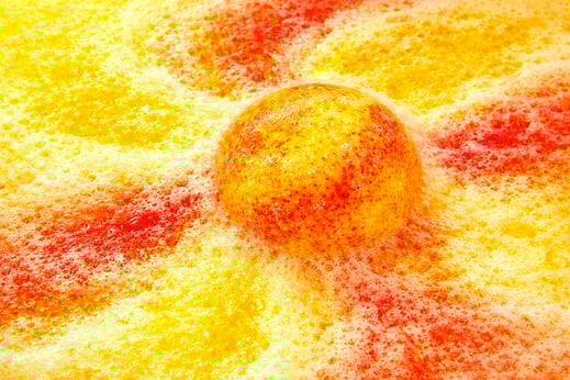 XL bath bomb producing golden yellow and orange foam with heavy fizz.
