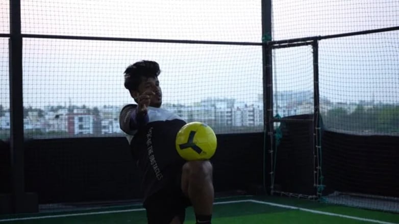 a man holding a soccer ball in a cage