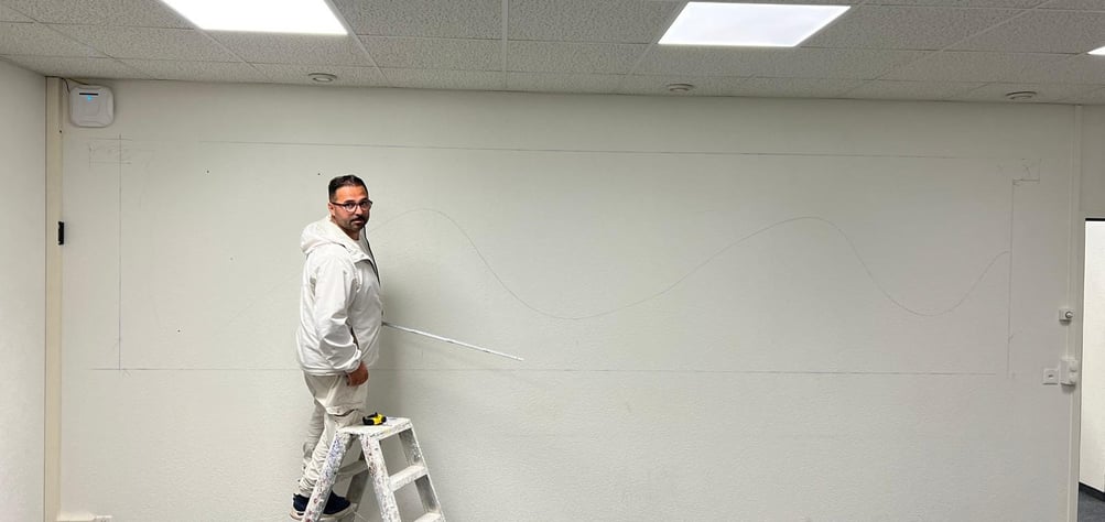 Homme sur un escabeau prenant des mesures.