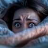 individu sous les couvertures yeux ouverts évoquant des troubles du sommeil