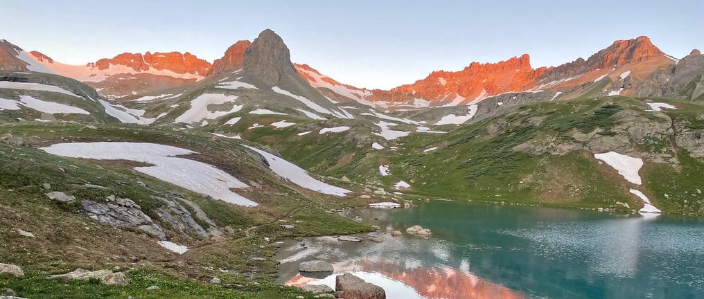a beautiful mountain view near a lake with the sun rising outside