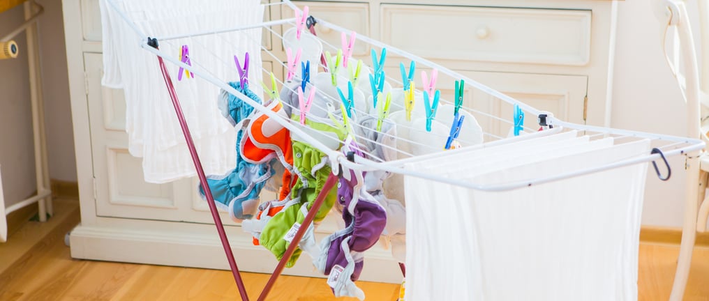 a laundry basket with cloth diapers hanging on a clothes rack