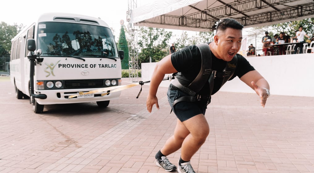 a man pulling a bus in a strongman competition