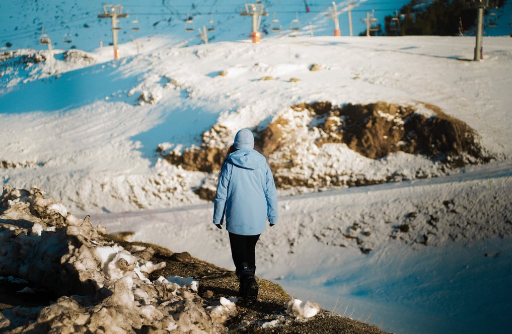 Une femme qui marche avec une veste bleue de dos 