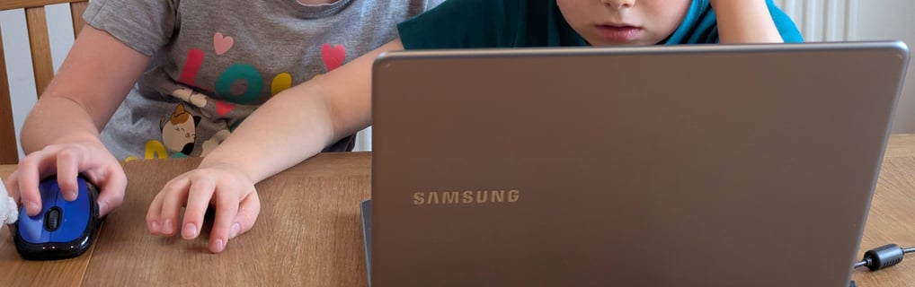 Two primary-age kids being creative with a laptop