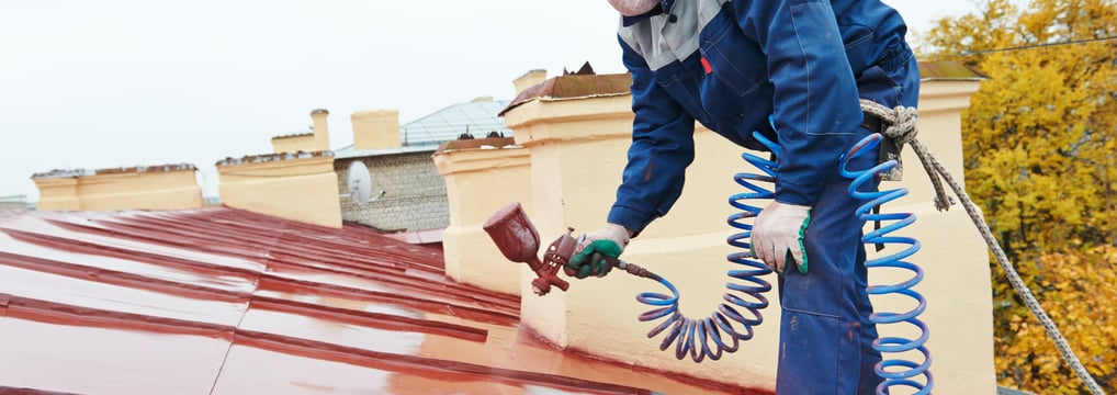 a man in a helmet painting a roof