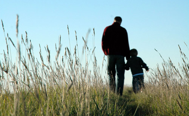a man and a child are standing in tall grass
