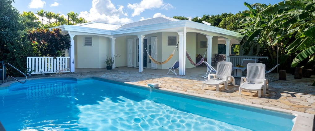 A house in Martinique with a pool, hammocks, and banana trees