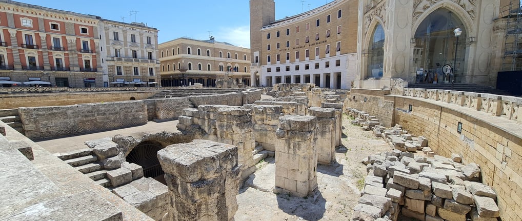 "Roman amphitheater in Lecce, Italy—ancient ruins in the heart of the city, showcasing historic arch