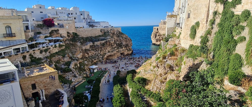 "Polignano a Mare Beach, Puglia – A breathtaking cove surrounded by dramatic limestone cliffs, with 