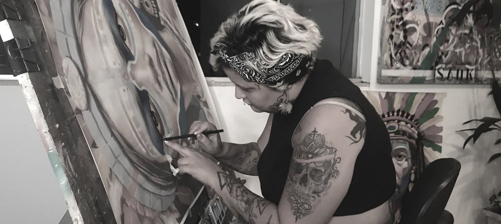 Amanda Amorim no ateliê aplicando técnicas de colagem em uma nova obra de arte contemporânea.