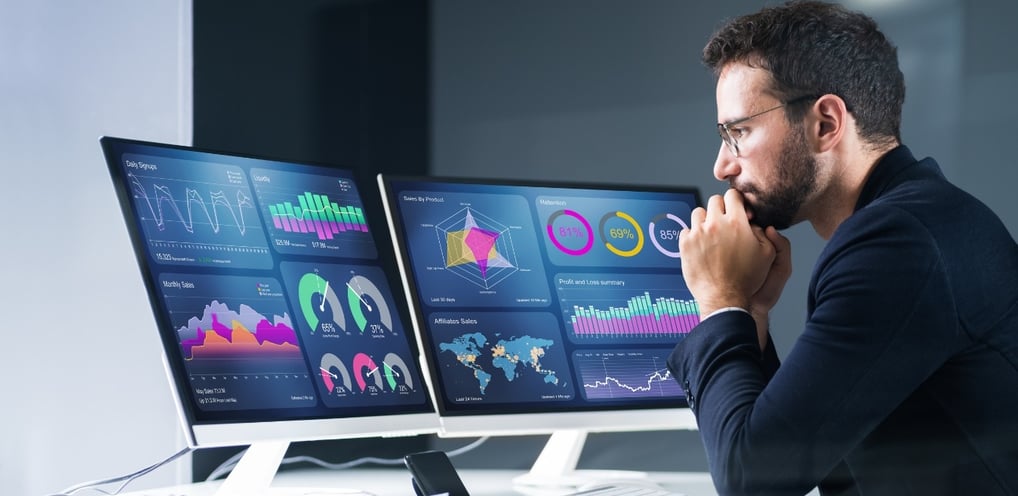 a man sitting at a desk with two monitors and a laptop-digital marketing institution