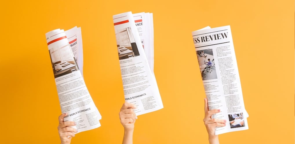 three hands holding up newspapers and a newspaper-digital marketing institution