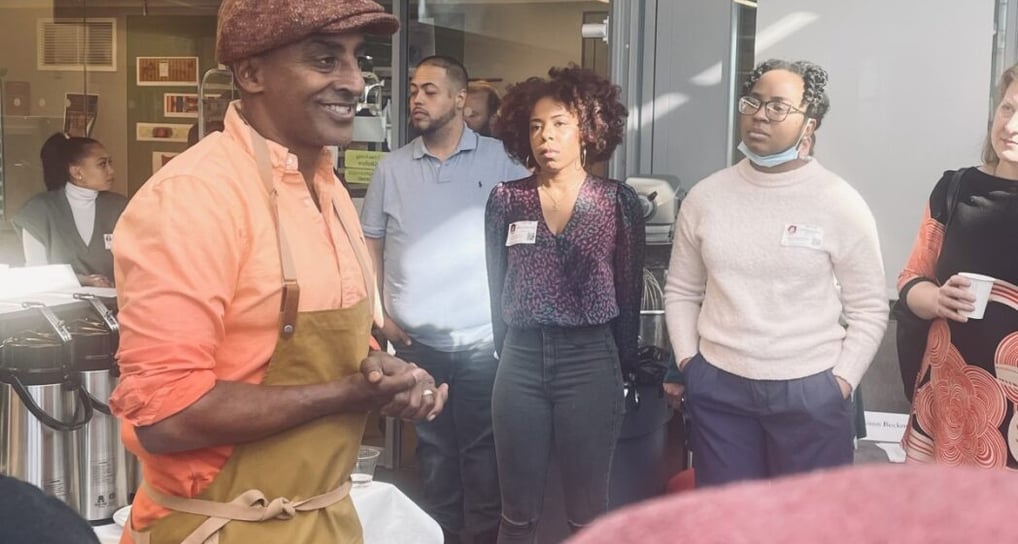 a group of people standing around a table with chef marcus samuelsson