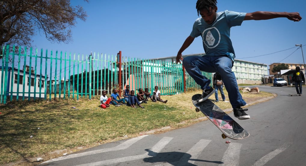 a man in a blue shirt is doing a trick on a skateboard