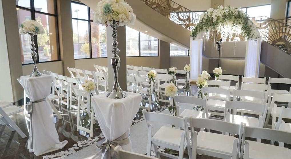 a wedding ceremony with white chairs and white chairs