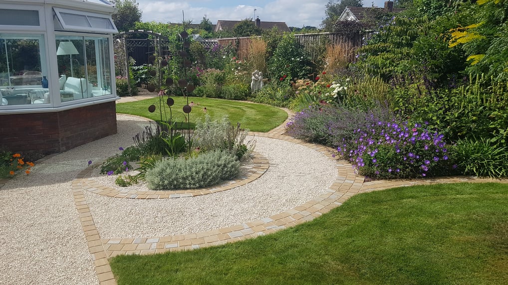 Artistic pathway and concentric circle garden feature made with sandstone setts and cotswold gravel.