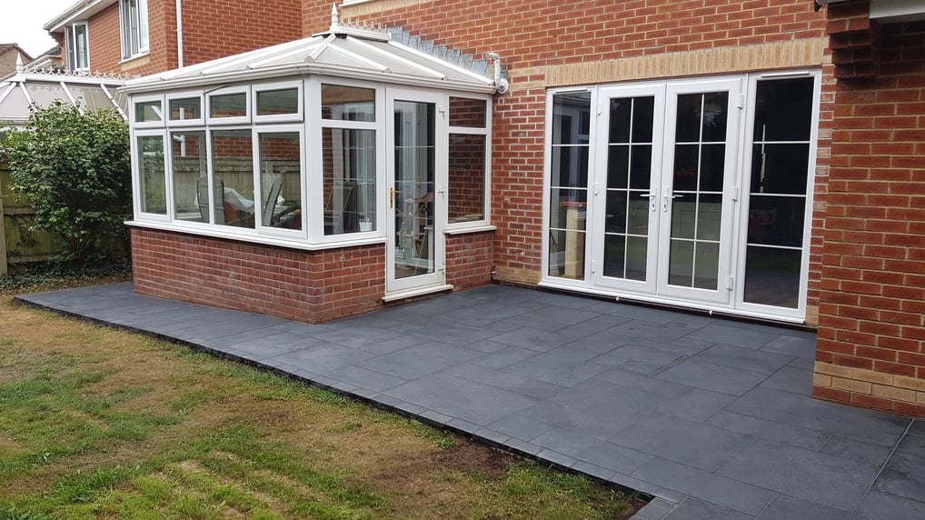 Patio made from black limestone built against a red brick house.