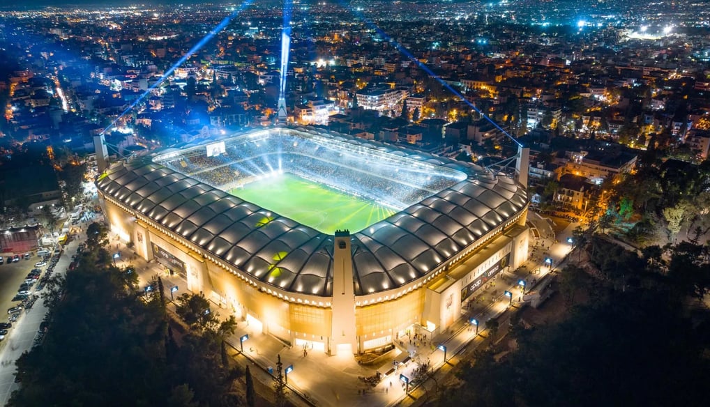 Luftaufnahme des Agia-Sofia-Stadions in Athen, Heimstätte des Fußballclubs AEK Athen, mit vollen Rängen bei Flutlicht und ein