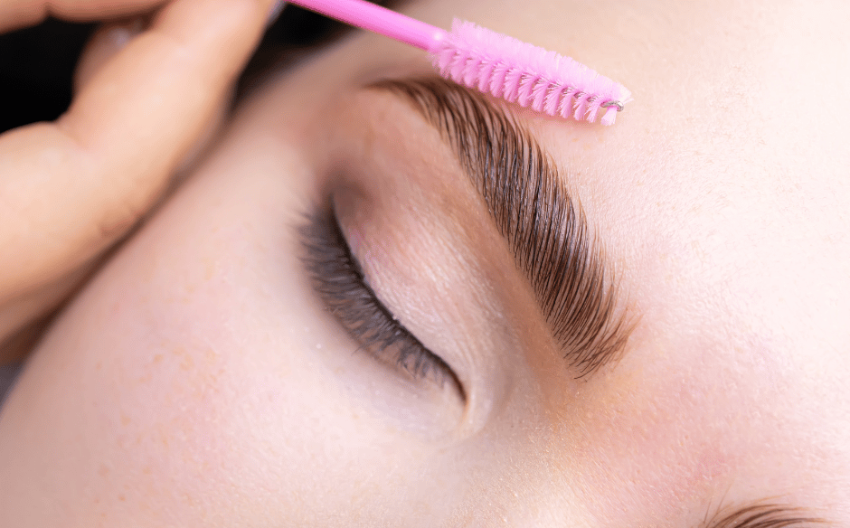 a woman brushing her brows after eyebrow lamination