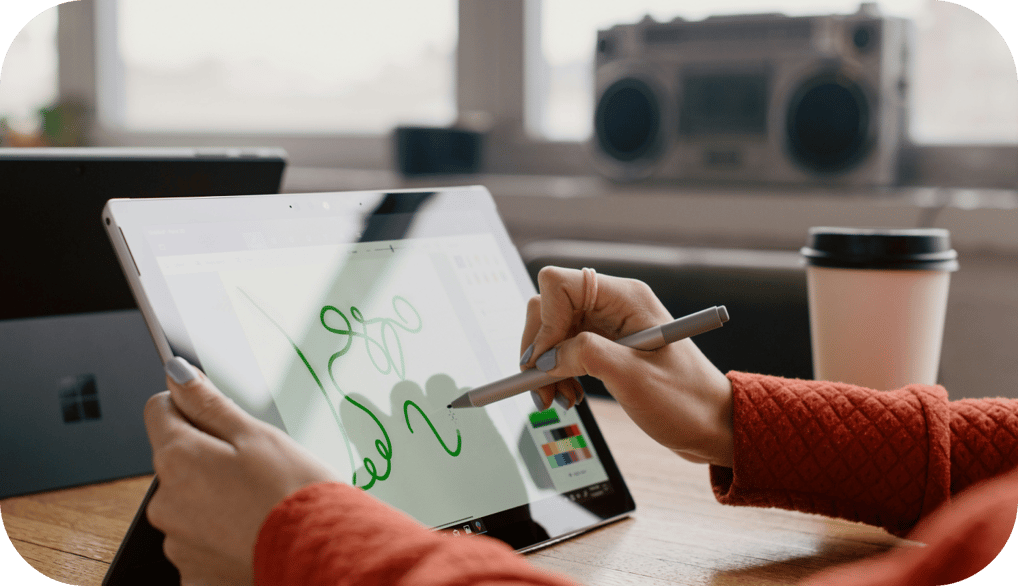 a person holding a pen and writing on a tablet